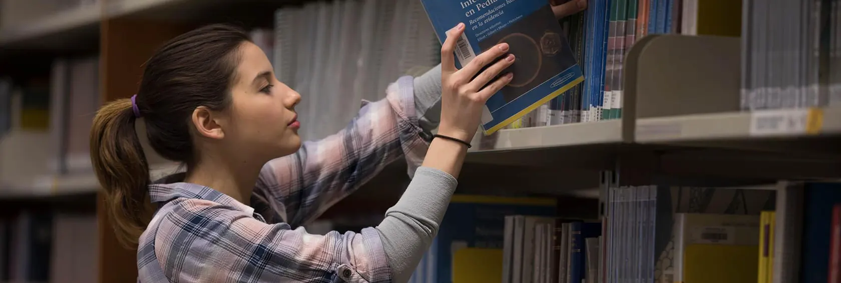 Mujer con mascarilla estudiando en la biblioteca